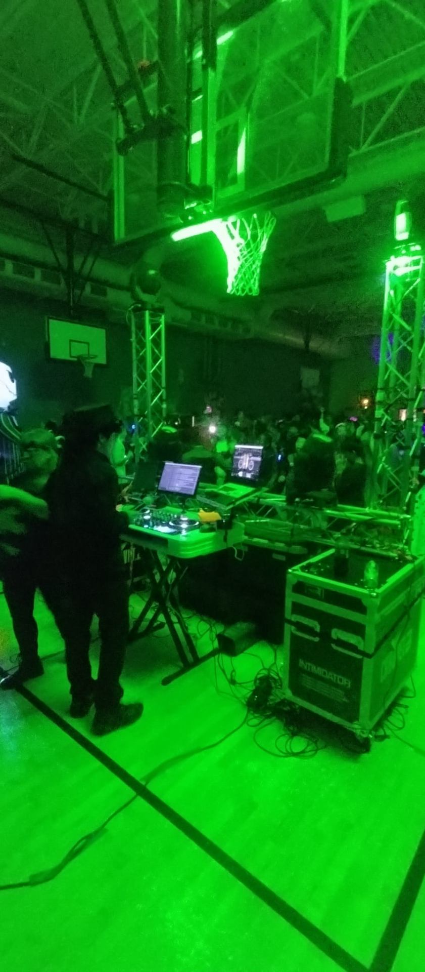 DJ setup on truss lit in green at a school gym dance
