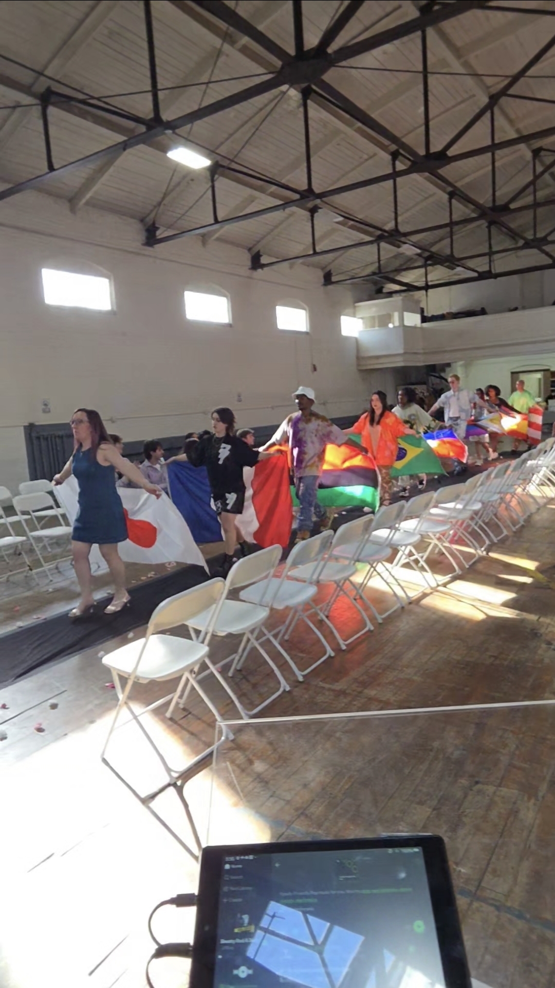 Community members carrying flags in a cultural procession during an organizational celebration
