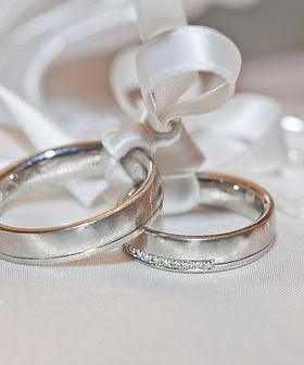 Pair of wedding rings resting on white satin ribbon