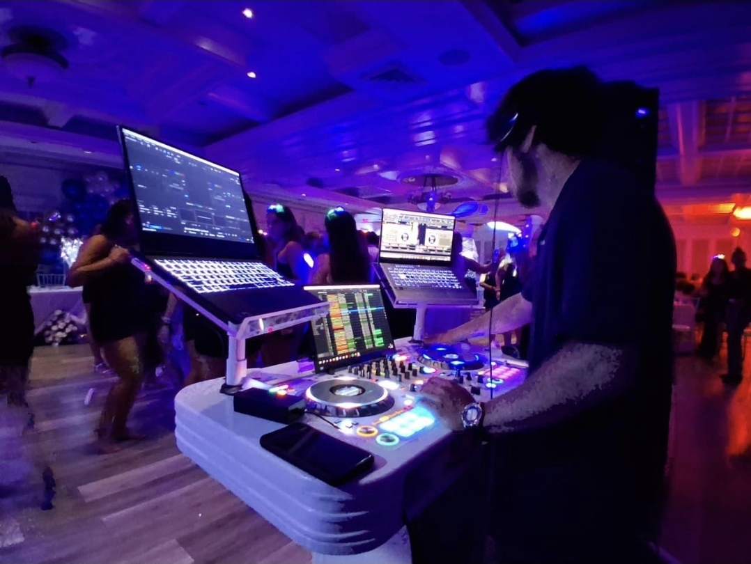 DJ Aiden Jules performing at a Sweet 16 with a packed dance floor and vibrant purple lighting