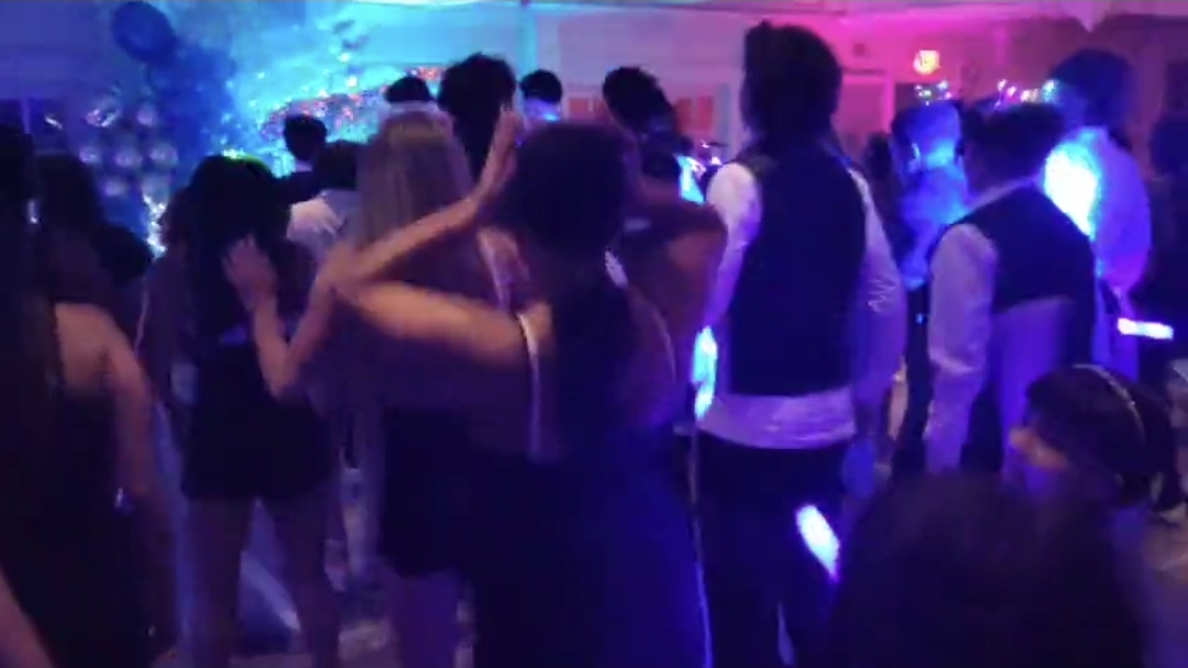 Family and friends slow dancing together under soft blue and purple lighting at a Quinceañera