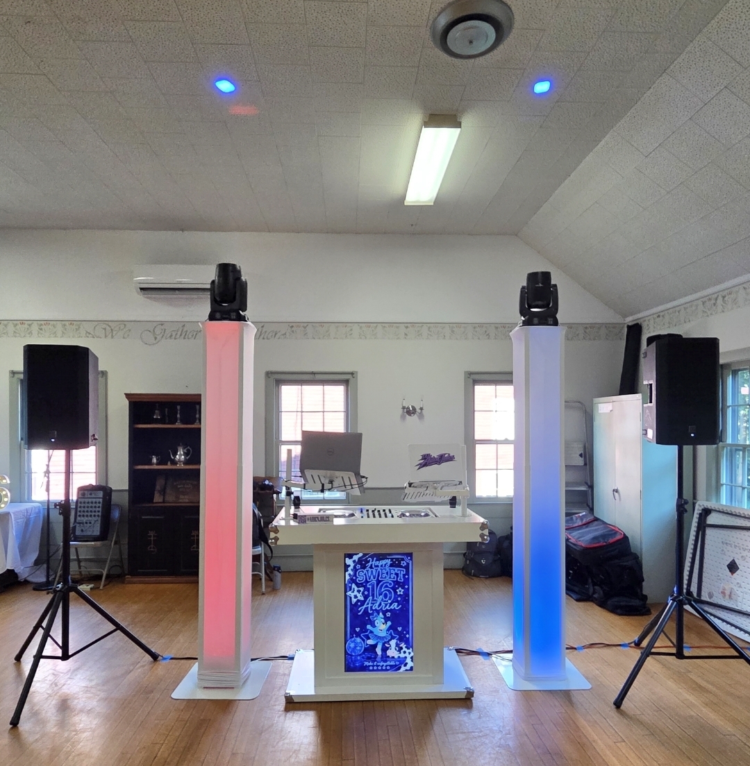 Sweet 16 private party setup with white DJ booth, moving-head lights on tall totems, and speakers in a decorated hall