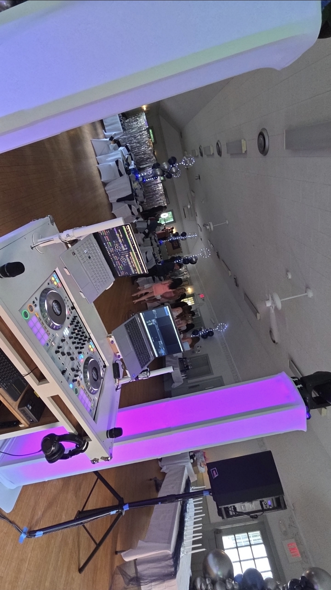 DJ Aiden Jules booth with mixer, laptops, and glowing pink uplight at a Sweet 16 reception