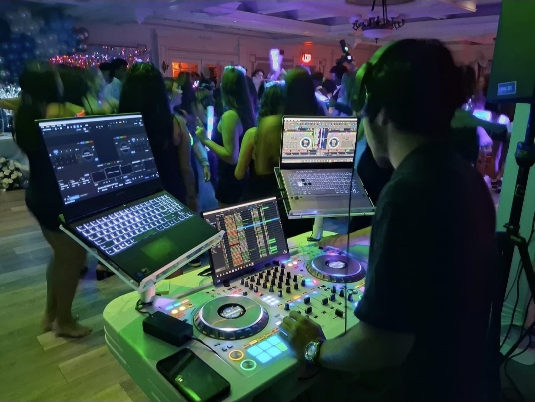 DJ booth with dual laptops mixing at a Sweet 16 celebration