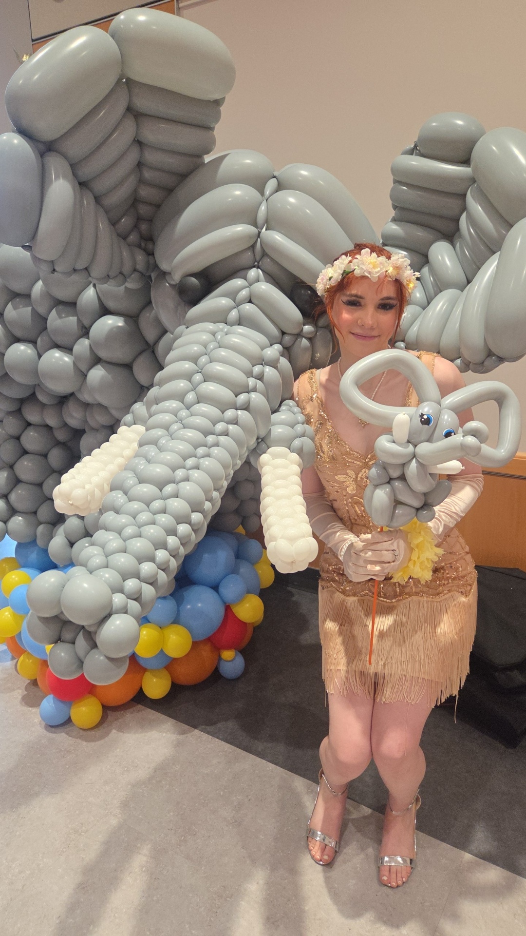 Balloon elephant sculpture beside a costumed performer at a college campus celebration