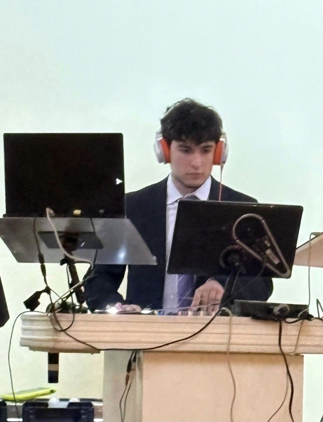 DJ Aiden Jules in a suit performing behind twin laptops at an elegant private reception